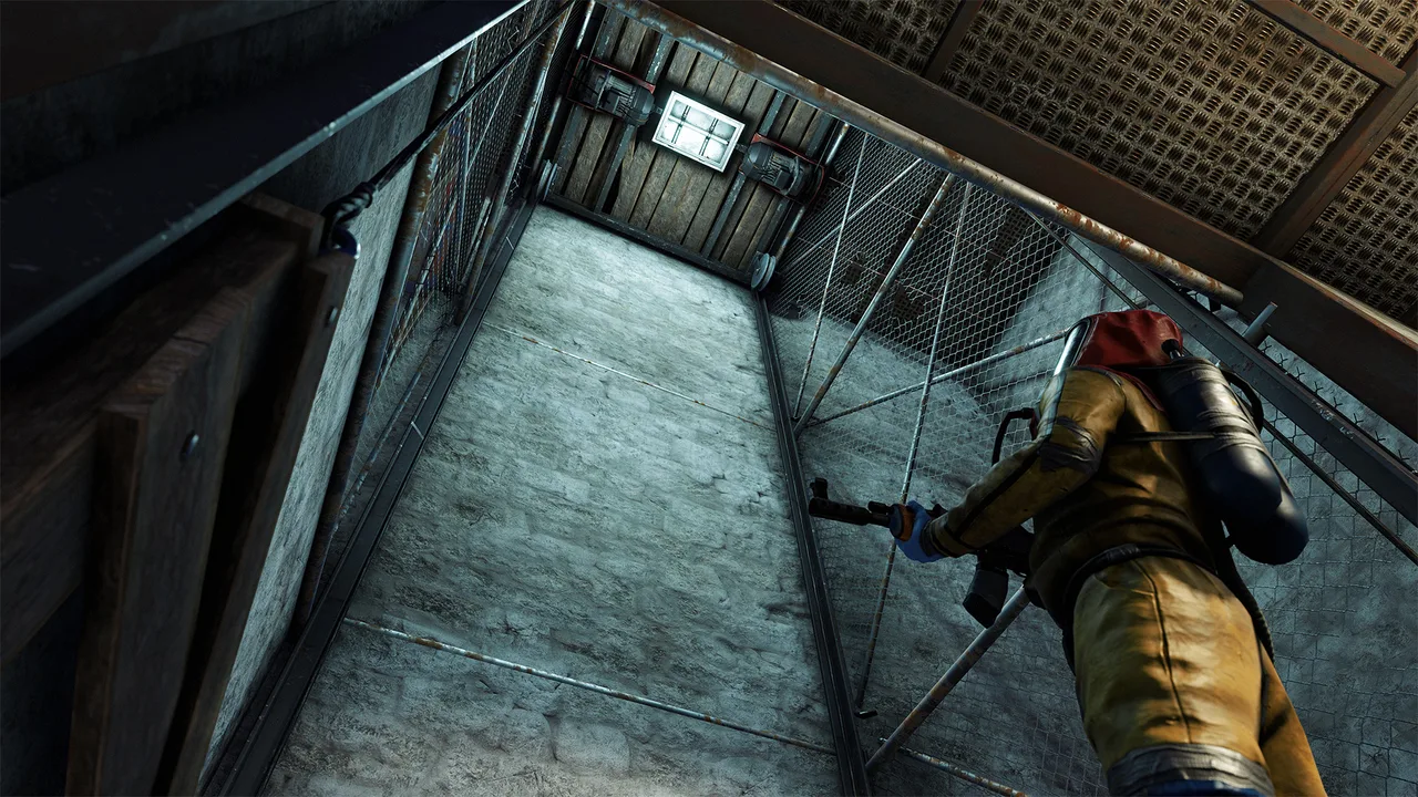 Игрок в костюме Hazmat с автоматом стоит в сетчатой шахте лифта Rust, наверху видны ролики и лампа механизма