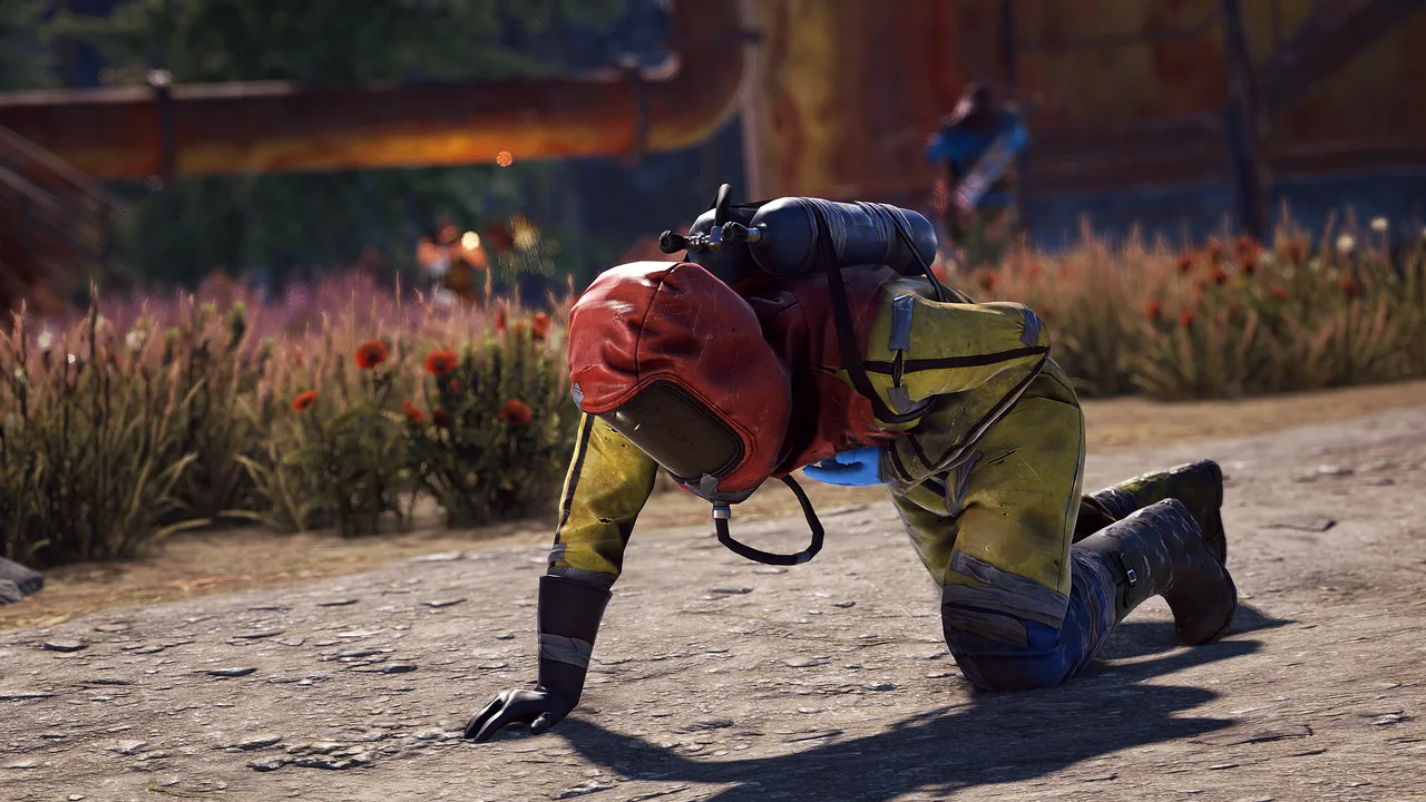 Раненый игрок Rust в жёлтом костюме ползёт по бетонной дороге у монумента, на фоне маки и ржавые трубы