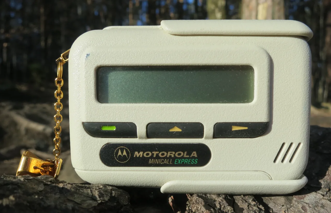 Чёрный пейджер Motorola Minicall Express 1990-х годов с жидкокристаллическим экраном и кнопками на белом фоне