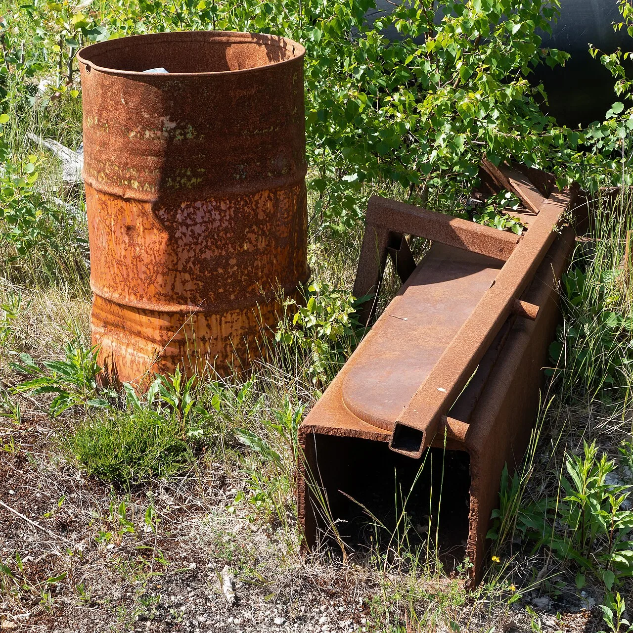 Ржавая металлическая бочка среди металлолома — в Rust из таких бочек вдоль дорог добывают скрап и компоненты